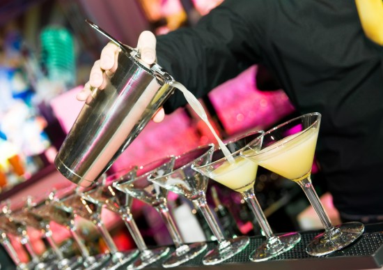 barman-pouring-a-row-of-drinks-550x387